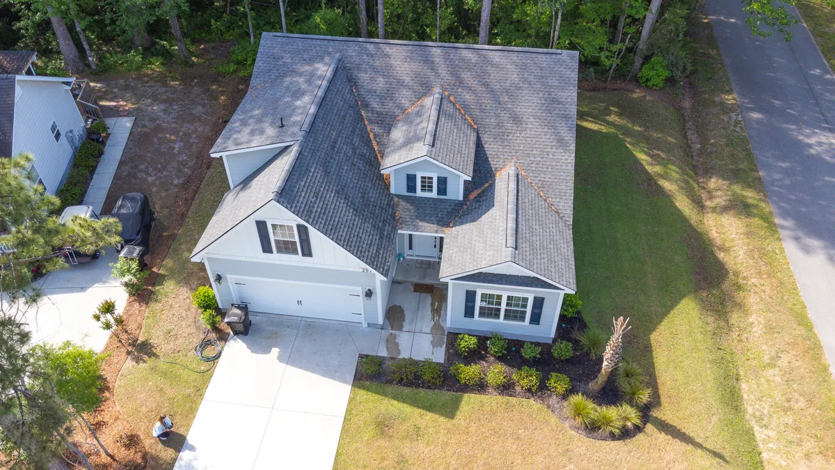 This image shows the inviting front porch and landscaped yard of the home, framed by lush greenery and a welcoming roofline. The space exudes a sense of relaxation and anticipation for gathering after a long day on the golf course.