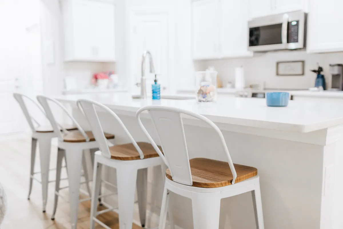 A welcoming kitchen scene featuring a central island with bar stools, a visible sink, and modern kitchen appliances. The layout clearly allows for collaborative cooking and socializing, with ample countertop space for meal prep or gathering.